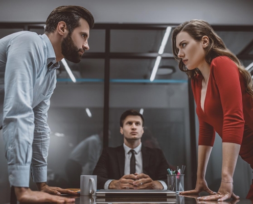 angry couple staring at eachother over office table during divorce mediation