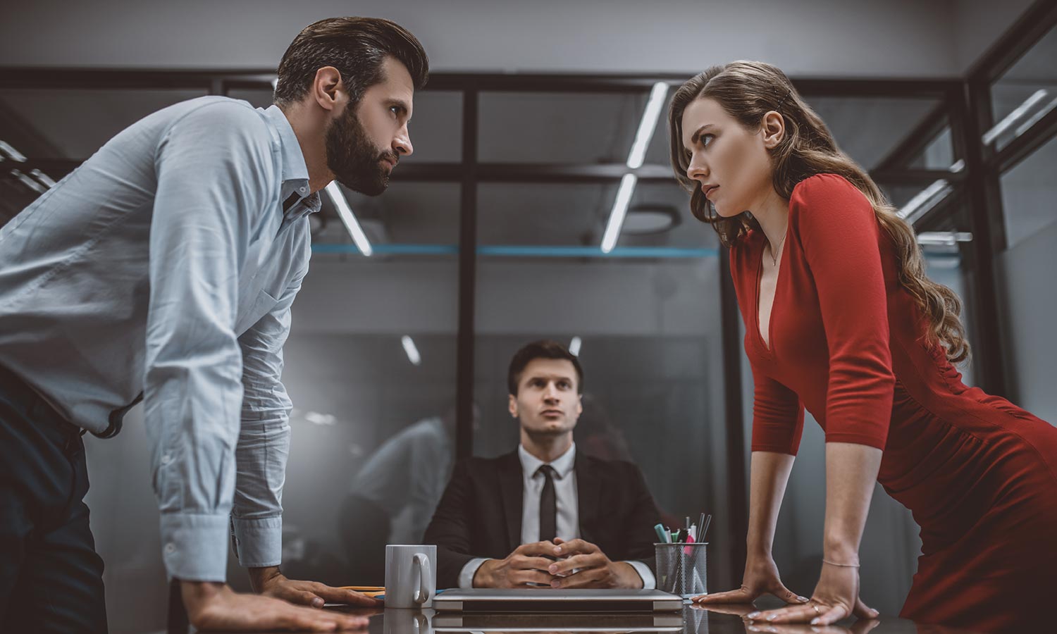 angry couple staring at eachother over office table during divorce mediation