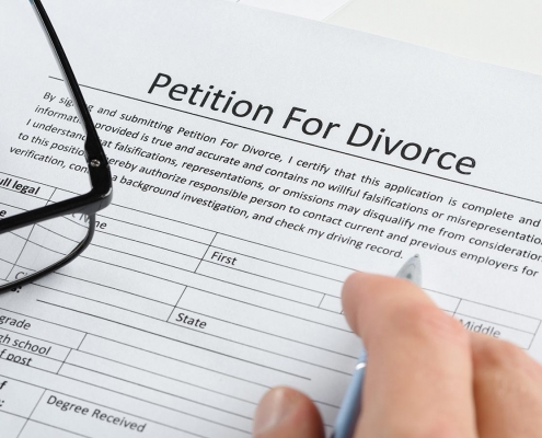 Close-up Of Hand With Pen On Petition For Divorce Paper