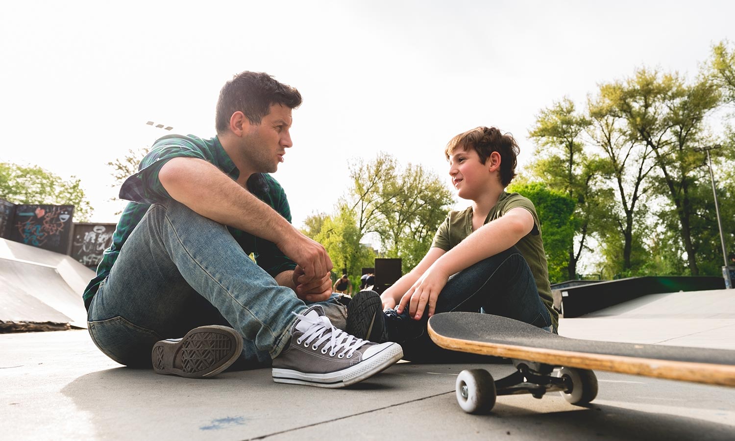 Father having a warm conversation with son at skate park