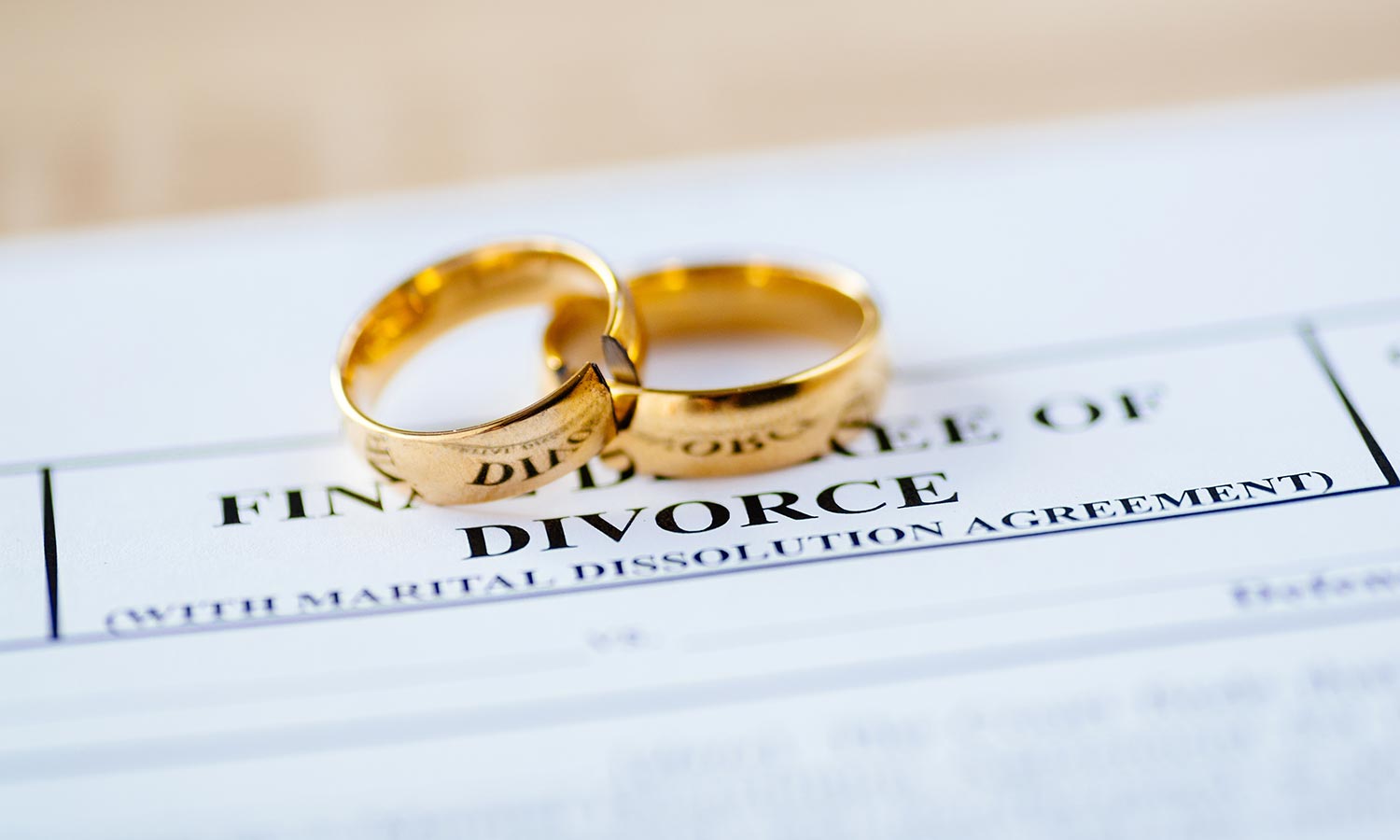 Two broken golden wedding rings divorce decree document